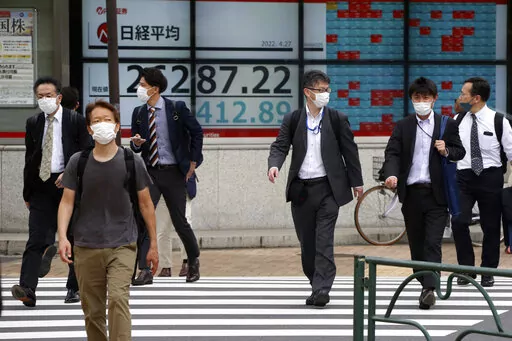 People walk by an electronic stock board of a securities firm in Tokyo, Wednesday, April 27, 2022. Asian shares retreated on Wednesday, echoing a broad decline on Wall Street and driven by worries about how the war in Ukraine may push prices for oil and other commodities higher.(AP Photo/Koji Sasahara)