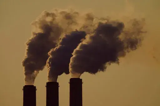 In this Sept. 18, 2021 photo, emissions rise from the smokestacks at the Jeffrey Energy Center coal power plant as the suns sets, near Emmett, Kans. As climate change bakes the planet, dozens of nations including the U.S. and many local governments are putting a price tag on greenhouse gas emissions that are causing more floods, droughts and other destructive events. (AP Photo/Charlie Riedel, File)