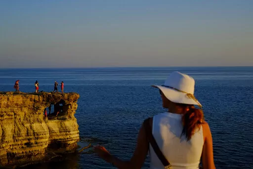 Tourists visit the sea caves during sunset at in southern coastal resort of Ayia Napa in southeast Mediterranean island of Cyprus, Sunday, May 29, 2022. Hundreds of Russian and Ukrainian Orthodox faithful visiting Cyprus would stream daily past the icon of the Virgin Mary at Kykkos Monastery to venerate the relic that tradition dictates was fashioned by Luke the Evangelist and blessed by the Virgin herself. But a European Union ban on flights to and from Russia as a result of Russia's invasion o