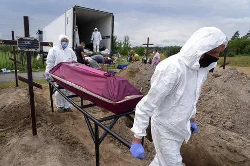 Workers carry a coffin with unidentified remains of a civilian murdered by the Russian troops during Russian occupation in Bucha, on the outskirts of Kyiv, Ukraine, Thursday, Aug. 11, 2022. Eleven unidentified bodies exhumed from a mass grave were buried in Bucha Thursday. (AP Photo/Efrem Lukatsky)