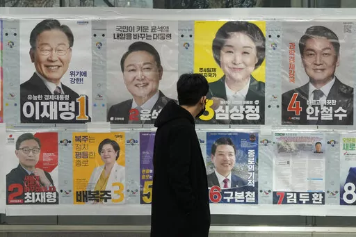 A man watches posters of presidential candidates on a street in Seoul, South Korea, March 3, 2022. Tens of millions of South Koreans are expected to vote Wednesday, March 9 to choose their new president. The winner will take office on May 10 for a single five-year term. Whoever wins, a new leader will be tasked with resolving various economic woes, easing threats from nuclear-armed North Korea and healing a nation sharply split along the lines of ideology, generation and gender. (AP Photo/Ahn Yo