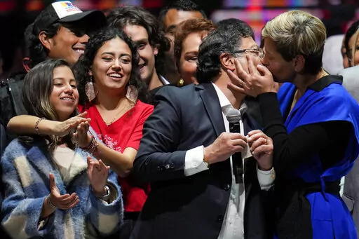 Veronica Alcocer kisses her husband, President elect Gustavo Petro, under the look of their daughters Antonella, left, and Sofia as they celebrate before supporters after he won a runoff presidential election in Bogota, Colombia, Sunday, June 19, 2022. (AP Photo/Fernando Vergara)