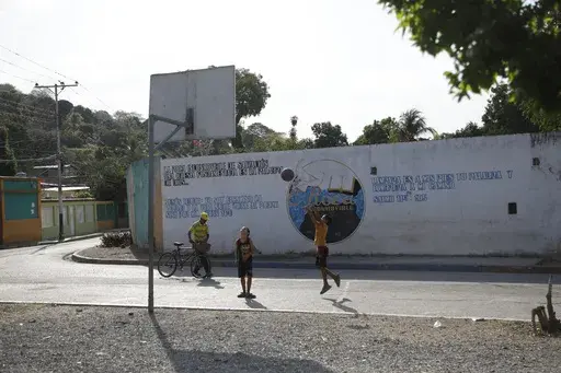 A child shoots a basketball on a street court in Tocorón, Venezuela, Saturday, March 22, 2025. (AP Photo/Cristian Hernandez)