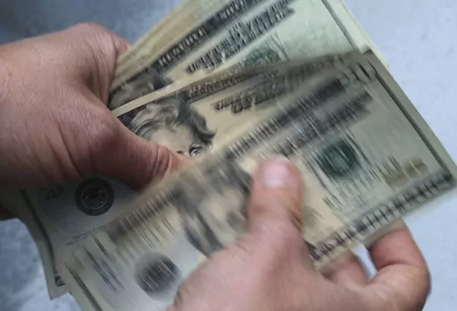 FILE- In this June 15, 2018, file photo, twenty dollar bills are counted in North Andover, Mass. Nearly a quarter of millennials are caregivers for an adult, according to a 2020 AARP survey. And a 2020 survey from insurance marketplace GoHealth found that 1 in 3 millennials are supporting their parents financially, and more than a quarter help manage their parents’ health care. (AP Photo/Elise Amendola, File)