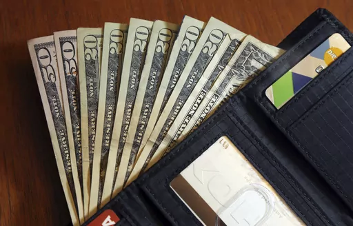 In this June 15, 2018, file photo, cash is fanned out from a wallet in North Andover, Mass. "Buy now, pay later” plans let you break up your purchase into smaller installments that you pay over a series of weeks or months. Wedding merchants now partner with buy now, pay later providers to offer these payment plans to customers, and some companies focus solely on buy now, pay later for weddings. (AP Photo/Elise Amendola, File)