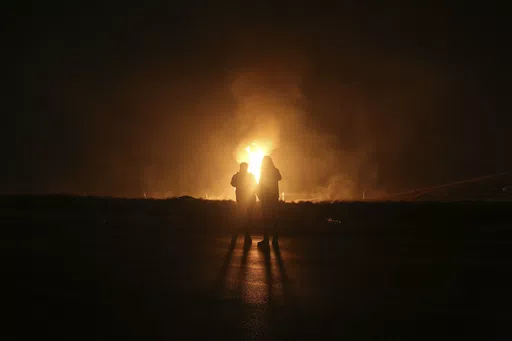 Two men look at flames after a natural gas pipeline explodes outside the city of Boroujen in the western Chaharmahal and Bakhtiari province, Iran, in early Wednesday, Feb. 14, 2024. Explosions struck a natural gas pipeline in Iran early Wednesday, with an official blaming the blasts on a "sabotage and terrorist action" in the country as tensions remain high in the Middle East amid Israel's war on Hamas in the Gaza Strip. (Reza Kamali Dehkordi/Fars News Agency via AP)