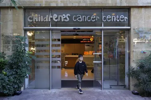 Mohammad Mousawi, 8, a displaced boy from the southern suburb of Beirut who suffers from leukaemia, steps out the entrance of the Children's Cancer Center of Lebanon, in Beirut, Lebanon, Friday, Nov. 15, 2024. (AP Photo/Hussein Malla)