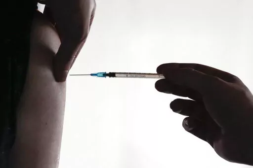 A doctor administers a COVID-19 vaccine to a man, inside the Klunkerkranich restaurant and night club during an ongoing vaccination campaign of the Clubkommission in Berlin, Germany, Wednesday, Jan. 5, 2022.  On Friday, Sept. 16, The Associated Press reported on stories circulating online incorrectly claiming Germany has halted the use of all COVID-19 vaccines because they are unsafe.  (AP Photo/Markus Schreiber, File)