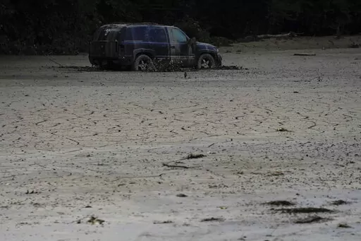 A vehicle is abandoned and surrounded by mud caused by massive flooding on Friday, Aug. 5, 2022, near Haddix, Ky. (AP Photo/Brynn Anderson)