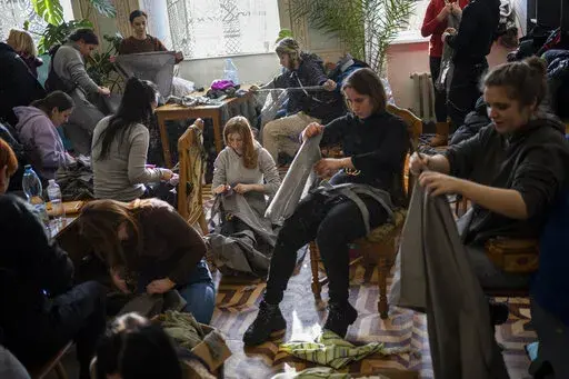 Ukrainian volunteers tear cloth into strips to make camouflage nets in Lviv, western Ukraine, Monday, Feb. 28, 2022. The Russian military assault on Ukraine went into its fifth day after Russian President Vladimir Putin ordered his nuclear forces put on increased alert, ratcheting up tensions yet further. (AP Photo/Bernat Armangue)