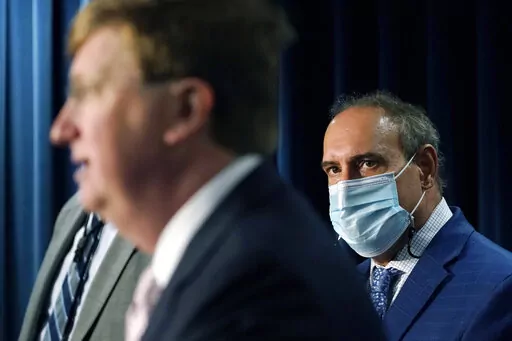 State Epidemiologist Dr. Paul Byers, right, listens to Mississippi Gov. Tate Reeves, left, at a news briefing, Aug. 24, 2021, in Jackson, Miss. The state's Department of Health said Wednesday, Jan. 11, 2023, that the 14th Mississippi child has died from COVID-19. (AP Photo/Rogelio V. Solis, File)