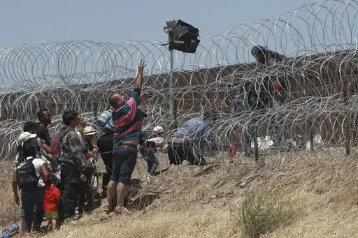 Migrants cross a barbed-wire barrier at the US-Mexico border, as seen from Ciudad Juarez, Mexico, Thursday, May 11, 2023. Migrants rushed across the Mexico border in hopes of entering the U.S. in the final hours before pandemic-related asylum restrictions are lifted. (AP Photo/Christian Chavez, File)