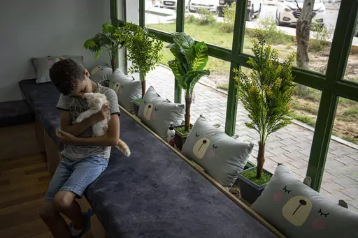 A Palestinian child enjoys the company of a cat on the opening day of Meow Cafe, Gaza City, Thursday, Aug 17, 2023. Amidst the challenges of life in the Gaza Strip, constrained by a 17-year blockade and ongoing conflicts, this first-ever cat cafe offers a unique space for relaxation and positive human-animal interaction. (AP Photo/Fatima Shbair)