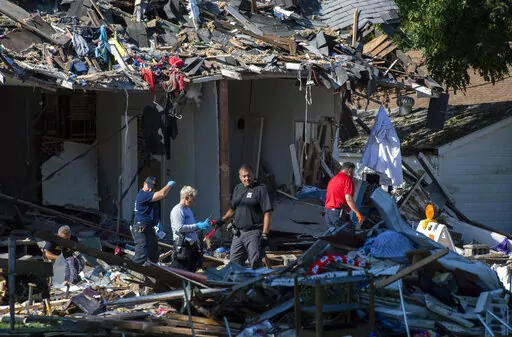 Emergency personnel search the debris, Thursday, Aug. 11, 2022, in  Evansville, Ind., as authorities work to determine the cause of a house explosion that killed three people and left another person hospitalized. The explosion the day before damaged 39 homes. (MaCabe Brown/Evansville Courier & Press via AP)