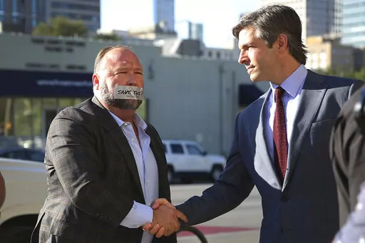 Alex Jones, left, arrives at the Travis County Courthouse in Austin, Texas, on July 26, 2022, with a piece of tape over his mouth that reads "Save the 1st." He shook hands with his lawyer, Andino Reynal. Although Jones portrays the lawsuit against him as an assault on the First Amendment, the parents who sued him say his statements were so malicious and obviously false that they fell well outside the bounds of speech protected by the constitutional clause. (Briana Sanchez/Austin American-Statesm
