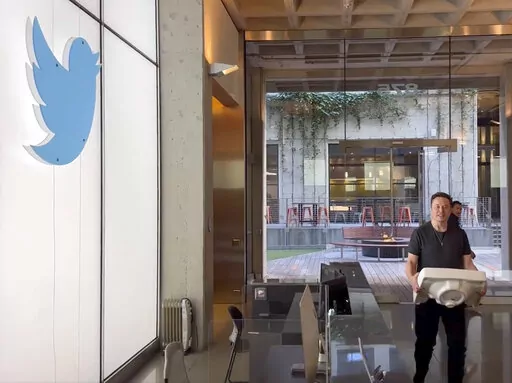 This image from the Twitter page of Elon Musk shows Musk entering Twitter headquarters carrying a sink through the lobby area on Wednesday, Oct. 26, 2022 in San Francisco.  Musk posted a video Wednesday showing him strolling into Twitter headquarters ahead of a Friday deadline to close his $44 billion deal to buy the company.  (Twitter page of Elon Musk via AP)