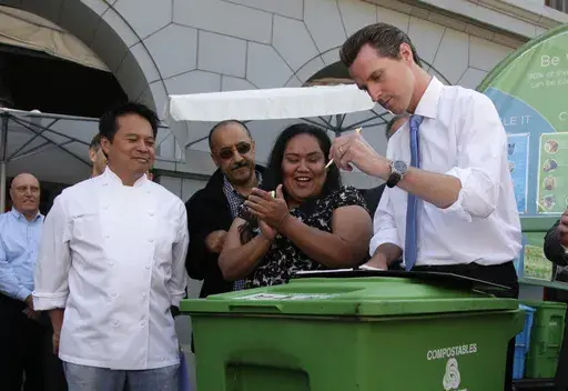 San Francisco Mayor Gavin Newsom, right, signs a mandatory recycling and composting ordinance on top of a compostable collection bin at the Ferry Building in San Francisco, June 23, 2009. Looking on at left is executive chef Charles Phan of The Slanted Door restaurant. (AP Photo/Eric Risberg, file)