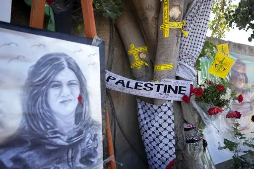Yellow tape marks bullet holes on a tree and a portrait and flowers create a makeshift memorial on o May 19, 2022, at the site where Palestinian-American Al-Jazeera journalist Shireen Abu Akleh was shot and killed in the West Bank city of Jenin. The Palestinian Authority on Saturday, July 2, 2022, said it has given the bullet that killed Al Jazeera journalist Shireen Abu Akleh to American forensic experts, taking a step toward resolving a standoff with Israel over the investigation into her deat