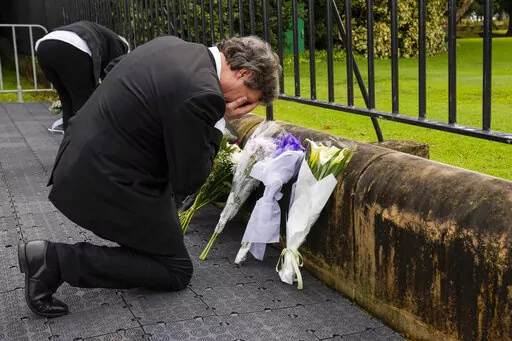A man reacts after laying flowers outside Government House following the passing of Queen Elizabeth II in Sydney, Australia, Friday, Sept. 9, 2022. Queen Elizabeth II, Britain's longest-reigning monarch and a symbol of stability in a turbulent era for her country and the world, died Thursday, Sept. 8 after 70 years on the throne. She was 96. (AP Photo/Mark Baker)