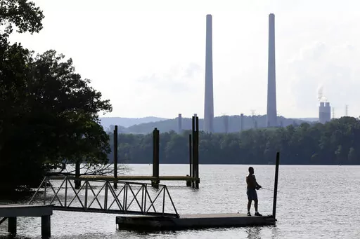 In this Aug. 7, 2019, file photo, a man fishes at William B. Ladd Park near the Kingston Fossil Plant in Kingston, Tenn. The largest public power company in the U.S. is launching a program to develop and fund new small modular nuclear reactors as part of its strategy to dramatically reduce greenhouse gas emissions. The board for the Tennessee Valley Authority on Thursday, Feb. 10, 2022 authorized the program to assess moving forward with new nuclear technology, with up to $200 million to be spen