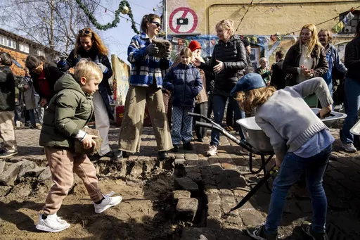 Citizens of the free village Christiania jointly dig up the cobblestones at Pusher Street, in Copenhagen, Denmark, Saturday April 6, 2024. After the cobblestones are removed, new water pipes and a new pavement will be laid on Pusher Street and nearby buildings will be renovated. That is the first step in an overall plan to turn the hippie oasis into an integrated part of the Danish capital area, although “the free state" spirit of creativity and community life is to be maintained. (Ida Marie O