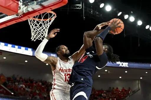 Houston forward J'Wan Roberts (13) blocks Jackson State forward Dylan Canoville (14) shot during the first half of an NCAA college basketball game, Monday, Nov 4, 2024, in Houston. (AP Photo/Maria Lysaker)
