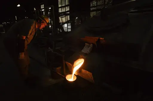 Craftsman Katsunori Suzuki takes molten iron into a bucket before carrying it back to his work section to make a cast iron pot manually at the Oigen foundry in Oshu, northeastern Japan, Thursday, May 16, 2024. (AP Photo/Hiro Komae)