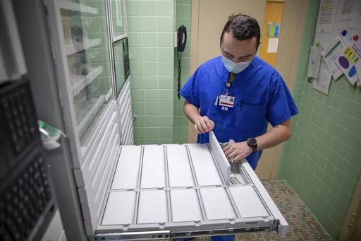 In this image provided by the U.S. Army, U.S. Air Force 2nd Lt. Kaelan Hayes, a clinical nurse assigned to the military medical team deployed to Brockton, Mass., gathers medication as part of the COVID-19 response operations at Signature Healthcare Brockton Hospital, March 15, 2022. (Sgt. Kaden D. Pitt/U.S. Army via AP)