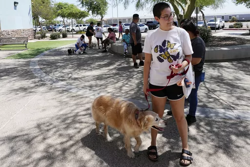 Rori Chang, of Glendale, Ariz., waits in line with her dog Ava to get microchipped at the Maricopa Country Animal Care & Control facility Friday, June 30, 2023, in Phoenix. Most of the U.S. may be looking forward to July Fourth celebrations for dazzling displays of fireworks or setting off firecrackers and poppers with their neighbors. Those with furry, four-legged family members — maybe not so much. They're searching for solutions to the Fourth of July anxiety that fireworks bring. (AP Photo/