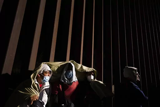 Four men from Cuba try to keep warm after crossing the border from Mexico and surrendering to authorities to apply for asylum on Nov. 3, 2022, near Yuma, Ariz. U.S. District Judge Emmet Sullivan on Tuesday, Nov. 15, ordered the Biden administration to lift Trump-era asylum restrictions that have been a cornerstone of border enforcement since the beginning of COVID-19. Sullivan ruled that Title 42 authority end immediately for families and single adults, saying it violates federal rule-making pro