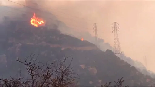 In this Saturday, Dec. 16, 2017, file image taken from video provided by the Santa Barbara County Fire Department, spot fires burn near power lines as heavy smoke fills the air from a wildfire in Santa Barbara, Calif. The nation's largest utility, Pacific Gas & Electric is poised to emerge from five years of criminal probation amid worries that it remains too dangerous to be trusted. Over the five years, the utility became an even more destructive force. More than 100 people have died and thousa