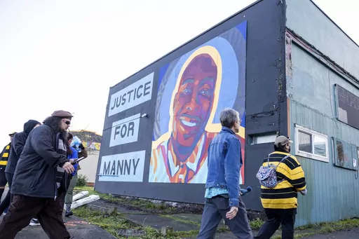 Protesters walk by a mural of Manny Ellis after the verdict is read during the trial of three Tacoma police officers in the death of Ellis, Dec. 21, 2023, at Pierce County Superior Court in Tacoma, Wash. Three Washington state police officers who were cleared of all criminal charges last month in the 2020 death of Ellis will each receive $500,000 to leave the Tacoma Police Department, according to documents released, Tuesday, Jan. 16, 2024. (AP Photo/Maddy Grassy)