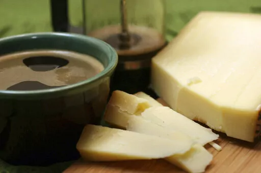 This Feb. 15, 2007 file photo shows a Gruyere cheese with a cup of Italian roast coffee. A federal judge has ruled that gruyere cheese does not have to come from the Gruyere region of Europe to be sold under the gruyere name. A consortium of Swiss and French cheesemakers from the region around of Gruyeres, Switzerland, sued in U.S. District Court in Virginia after the federal Trademark Trials and Appeals Board denied an application for trademark protections. (AP Photo/Larry Crowe, file)