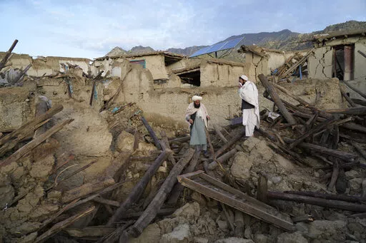 Afghans stand among destruction after an earthquake in Gayan village, in Paktika province, Afghanistan, Thursday, June 23, 2022. A powerful earthquake struck a rugged, mountainous region of eastern Afghanistan early Wednesday, flattening stone and mud-brick homes in the country's deadliest quake in two decades, the state-run news agency reported. (AP Photo/Ebrahim Nooroozi)
