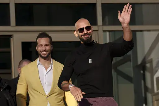 Andrew Tate waves as he exits the Bucharest Tribunal with his brother Tristan, in Bucharest, Romania, Thursday, Jan. 9, 2025. (AP Photo/Vadim Ghirda, File)