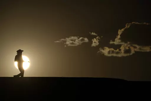 A person walks along a trail as the sun sets, Sunday, July 16, 2023, in Death Valley National Park, Calif. Human-caused global warming made July hotter for four out of five people on Earth, according to a new report issued Wednesday, Aug. 2, 2023, by Climate Central. (AP Photo/John Locher, File)