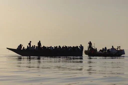 Migrants, left, are being rescued by volunteers of the Ocean Viking, a migrant search and rescue ship run by NGOs SOS Mediterranee and the International Federation of Red Cross (IFCR),  Saturday, Aug. 27, 2022, some 26 nautical miles south of the Italian Lampedusa island in the Mediterranean sea. 87 survivors, including 3 women, 25 minors were rescued in the rescue operation. (AP Photo/Jeremias Gonzalez)