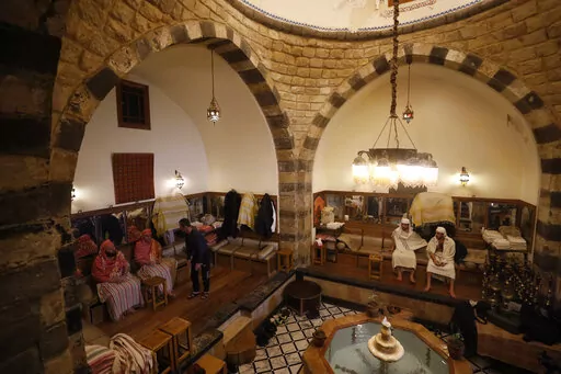 Patrons sit in a public bathhouse in Damascus, Syria, Saturday, Jan. 22, 2022. Syria's traditional public bathhouses, known as Hammamat, are picking up steam again due to electricity cuts during a particularly cold winter. With soaring fuel prices and barely enough electricity for hot water at home, Damascus' public baths say they are doing brisk business, and that the difficult times are helping keep the tradition alive. (AP Photo/Omar Sanadiki)
