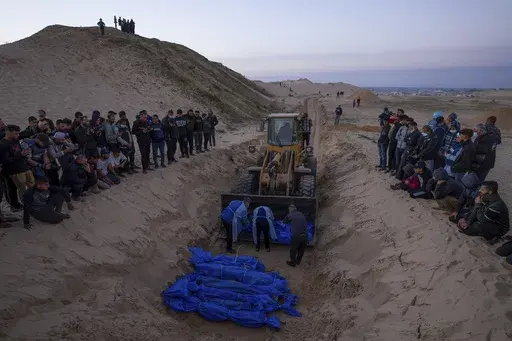 A bulldozer unloads the bodies of Palestinians killed in Israeli strikes and turned over by the Israeli military during a mass funeral in Rafah, Gaza Strip, Tuesday, Dec. 26, 2023. (AP Photo/Fatima Shbair, File)