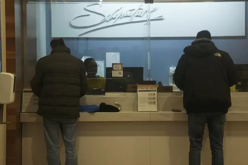 Customers do business at a branch of Signature Bank in New York, Monday, March 13, 2023. President Joe Biden is telling Americans that the nation's financial systems are sound. This comes after the swift and stunning collapse of two banks that prompted fears of a broader upheaval. (AP Photo/Seth Wenig)
