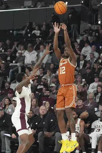 Texas guard Tramon Mark (12) attempts a three-point shot while defended by Mississippi State guard Shawn Jones Jr., left, during the first half of an NCAA college basketball game, Tuesday, March 4, 2025, in Starkville, Miss. (AP Photo/Rogelio V. Solis)