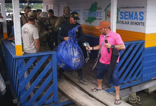 Federal police officers arrive at the pier with items found during a search for Indigenous expert Bruno Pereira and freelance British journalist Dom Phillips in Atalaia do Norte, Amazonas state, Brazil, Sunday, June 12, 2022. Divers from Brazil's firefighters corps found a backpack and laptop Sunday in the remote Amazon area where Pereira and Phillips went missing a week ago, firefighters said. (AP Photo/Edmar Barros)