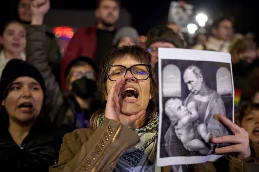 A woman shouts holding an altered version of a classic painting, depicting Russian President Vladimir Putin and Calin Georgescu, the independent candidate for Romanian presidency who won the first round of elections making it to the Dec. 8, runoff in Bucharest, Romania, Monday, Nov. 25, 2024. (AP Photo/Andreea Alexandru, File)