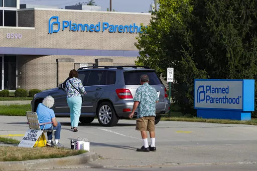 Abortion protesters attempt to hand out literature as they stand in the driveway of a Planned Parenthood clinic in Indianapolis, Aug. 16, 2019. Hospitals and abortion clinics in Indiana are preparing for the state's abortion ban to go into effect on Sept. 15, 2022. Starting Sept. 15, abortions will be permitted only in cases of rape and incest, before 10-weeks post-fertilization; to protect the life and physical health of the patient; and if a fetus is diagnosed with a lethal anomaly. The law al
