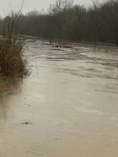 In this photo provided by Layton Hoyer, a red SUV is seen submerged in floodwater on Old Ritchey Road in Granby, Mo., early Friday, March 24, 2023. Hoyer rescued an elderly woman from the car. (Layton Hoyer via AP)