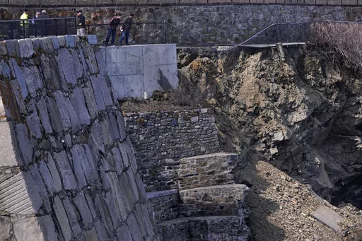 City officials and a private engineering group representatives peer down at debris of a collapsed section of the historic Cliff Walk, March 15, 2022, in Newport, R.I. Gov. Dan McKee issued a disaster declaration on Tuesday, June 13, 2023, that will allow the state Department of Transportation to apply for $10 million in emergency relief funds from the Federal Highway Administration. (AP Photo/Charles Krupa, File)