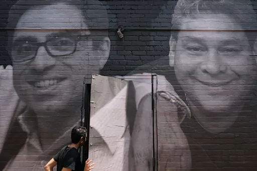 A woman steps through a door that is covered by a mural depicting American hostages and wrongful detainees who are being held abroad, July 20, 2022, in the Georgetown neighborhood of Washington. At left is Siamak Namazi, who has been in captivity in Iran since 2015. At right is Jose Angel Pereira, who has been imprisoned in Venezuela since 2017. The Biden administration has cleared the way for the release of five American citizens detained in Iran, including Namazi, by issuing a blanket waiver f