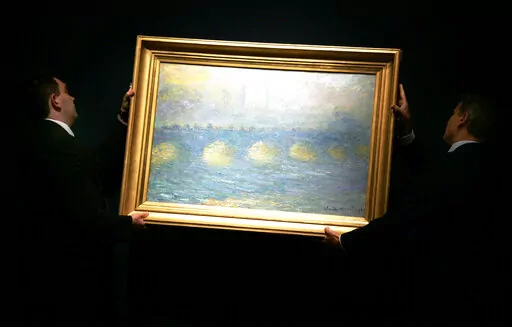 Two staff hang a Claude Monet 1904 painting 'Waterloo Bridge, temps couvert', for display at Christie's in London, Thursday, June 14, 2007. The painting was one of 60 pieces from the Paul G. Allen collection auctioned by Christie's in New York, on Wednesday, Nov. 9, 2022, bringing $1.5 billion in a single night. It sold for $64.5 million. (AP Photo/Sang Tan, File)