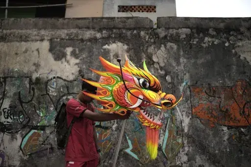 A member of dragon dance club Naga Merah Putih (Red White Dragon) which is named after Indonesian national colors, holds the head of a dragon puppet prepared for a performance in a Lunar New Year celebration, in Bogor, West Java, Indonesia, Sunday, Jan. 26, 2025. (AP Photo/Dita Alangkara)