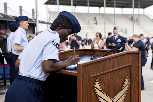 Airman 1st Class D'elbrah Assamoi, from Cote D'Ivoire, signs her U.S. certificate of citizenship after the Basic Military Training Coin Ceremony at Joint Base San Antonio-Lackland, in San Antonio, April 26, 2023. The Army and Air Force say they are on track to meet their recruiting goals in 2024, reversing previous shortfalls using a swath of new programs and policy changes. But the Navy, while improving, expects once again to fall short. (Vanessa R. Adame/U.S. Air Force via AP, File)